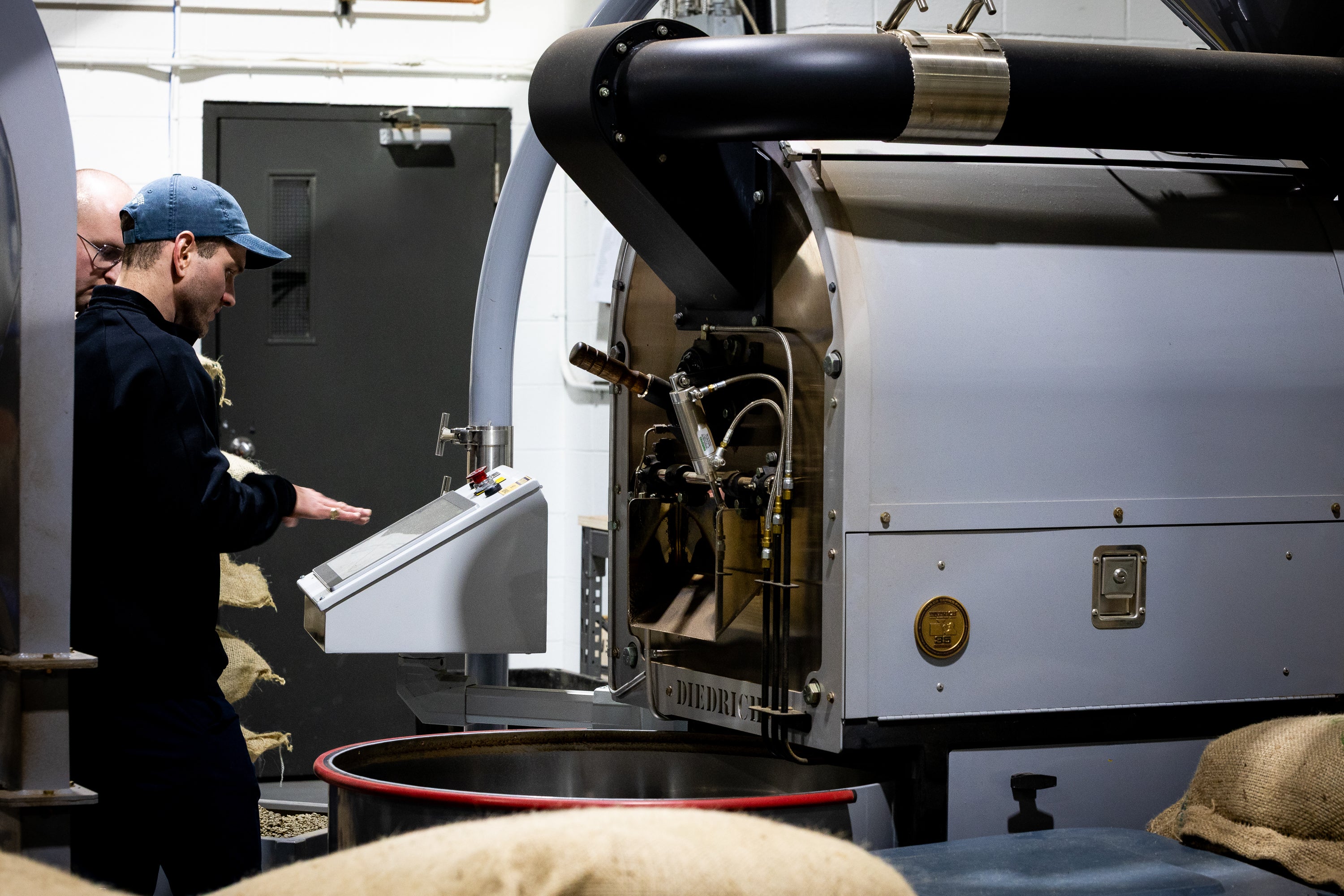 Person operating a coffee roasting machine in a warehouse setting